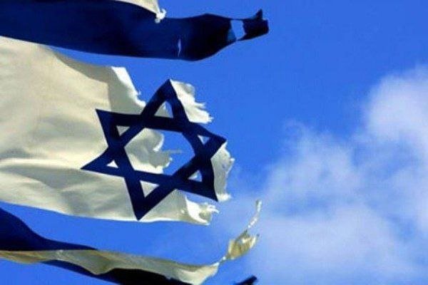 A tattered Israeli flag waves against a partly cloudy blue sky, held aloft by a visible flagpole.