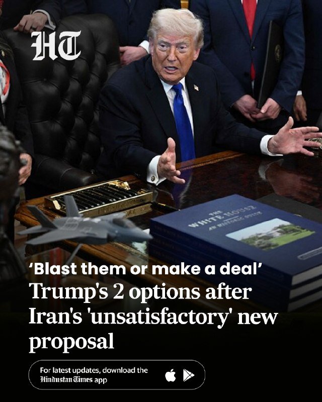 A man in a dark suit and blue tie sits at a desk with open palms, beside a book titled "The White House," surrounded by others in suits, with overlaid news headline text.