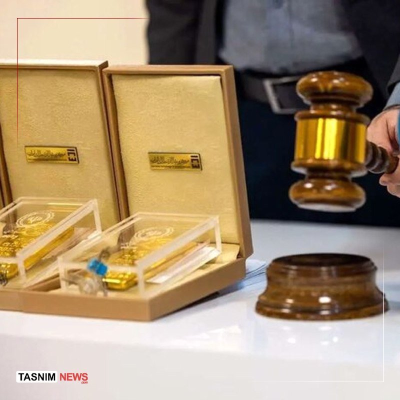 A person holds a wooden gavel beside two open boxes displaying gold bars at a table.