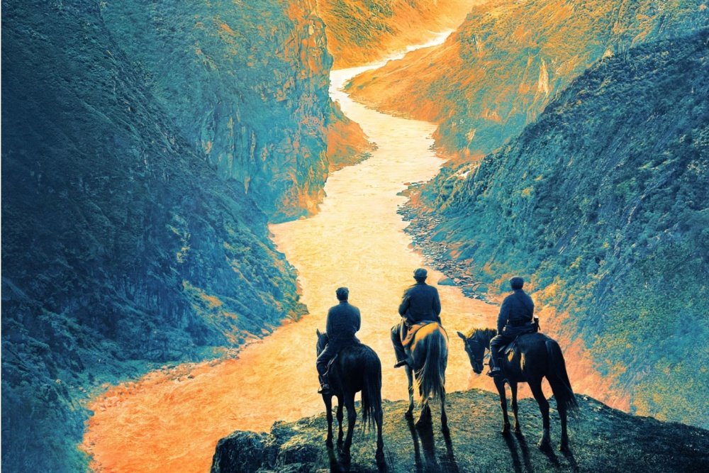 Three people on horseback stand at the edge of a steep cliff, overlooking a winding river flowing through a deep canyon with rocky, orange-lit slopes.