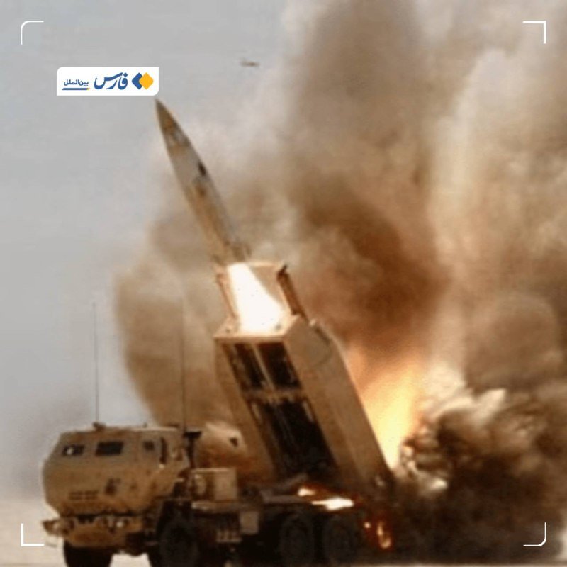 A military truck-mounted launcher fires a missile upward amid a massive cloud of smoke and flames, with a news logo in the upper left.