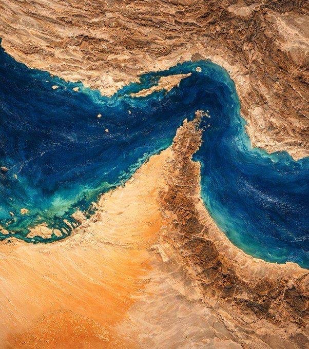 Satellite image showing a narrow blue waterway winding between arid, tan-colored desert landmasses.
