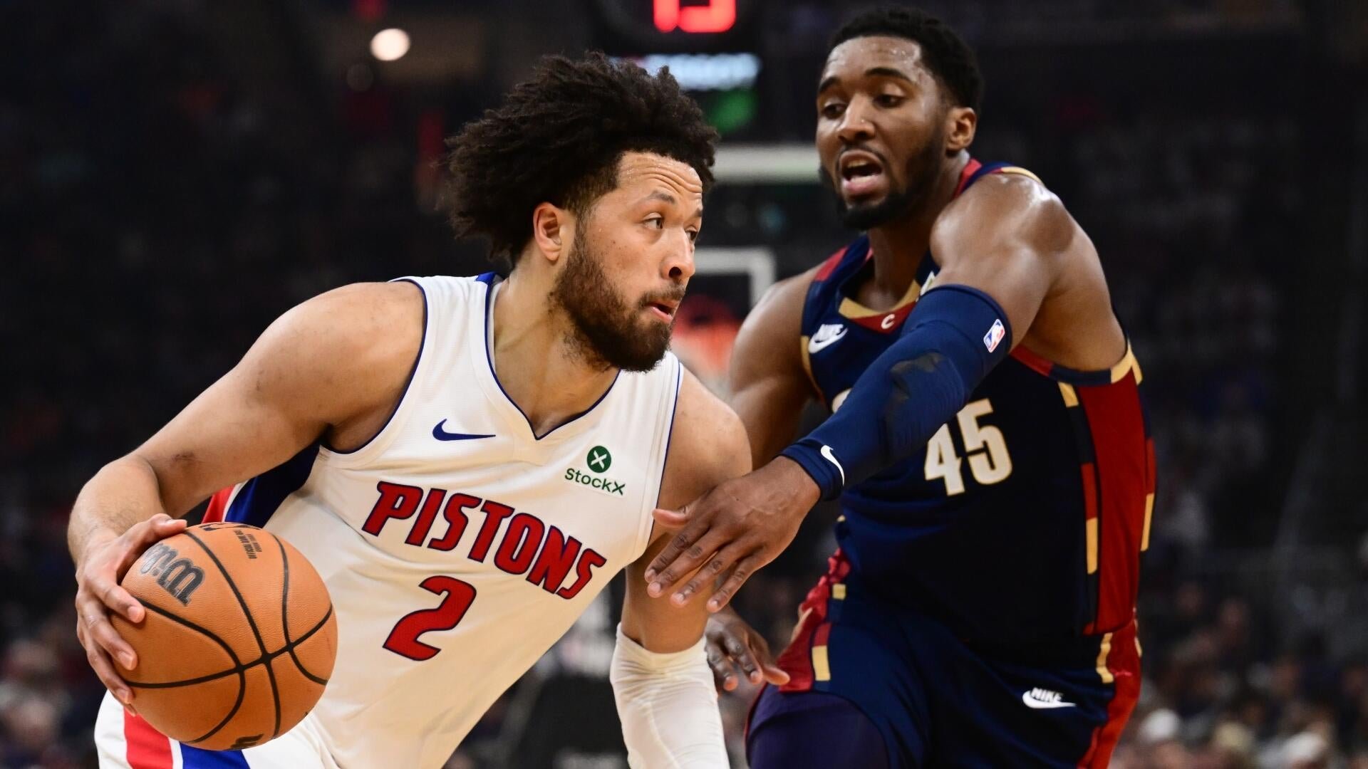 A Pistons player wearing number 2 drives with the basketball while being defended by a Cavaliers player wearing number 45 during a game.
