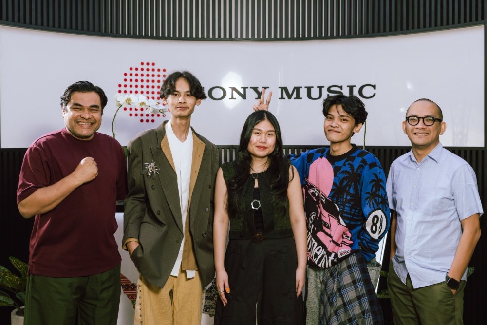 Five people pose together in front of a white wall displaying the "SONY MUSIC" logo.