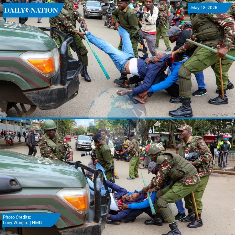 Uniformed officers in camouflage drag civilians on a street near a camouflage vehicle, with bystanders and motorcycles visible in the background.