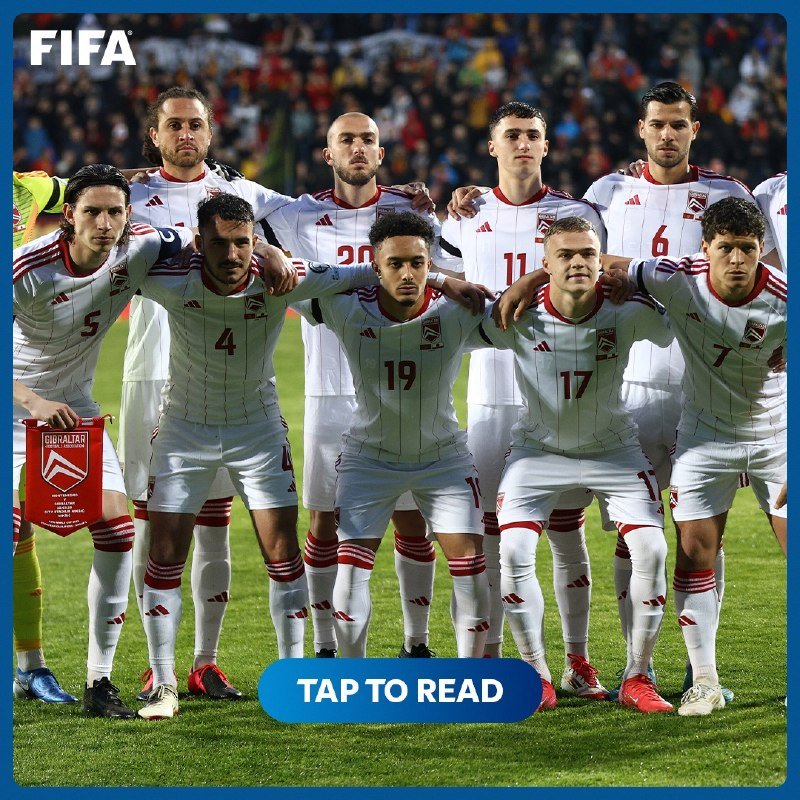 Eleven soccer players in white uniforms with red trim pose arm-in-arm for a team photo on a stadium field, with a "FIFA" logo and "TAP TO READ" button visible.