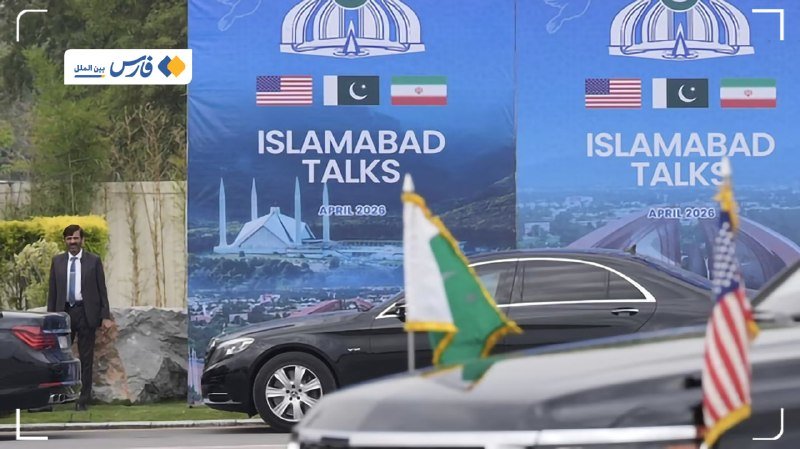 A man in a suit stands near black vehicles flying Pakistani and American flags in front of large blue banners reading "Islamabad Talks, April 2026" with US, Pakistani, and Iranian flags.