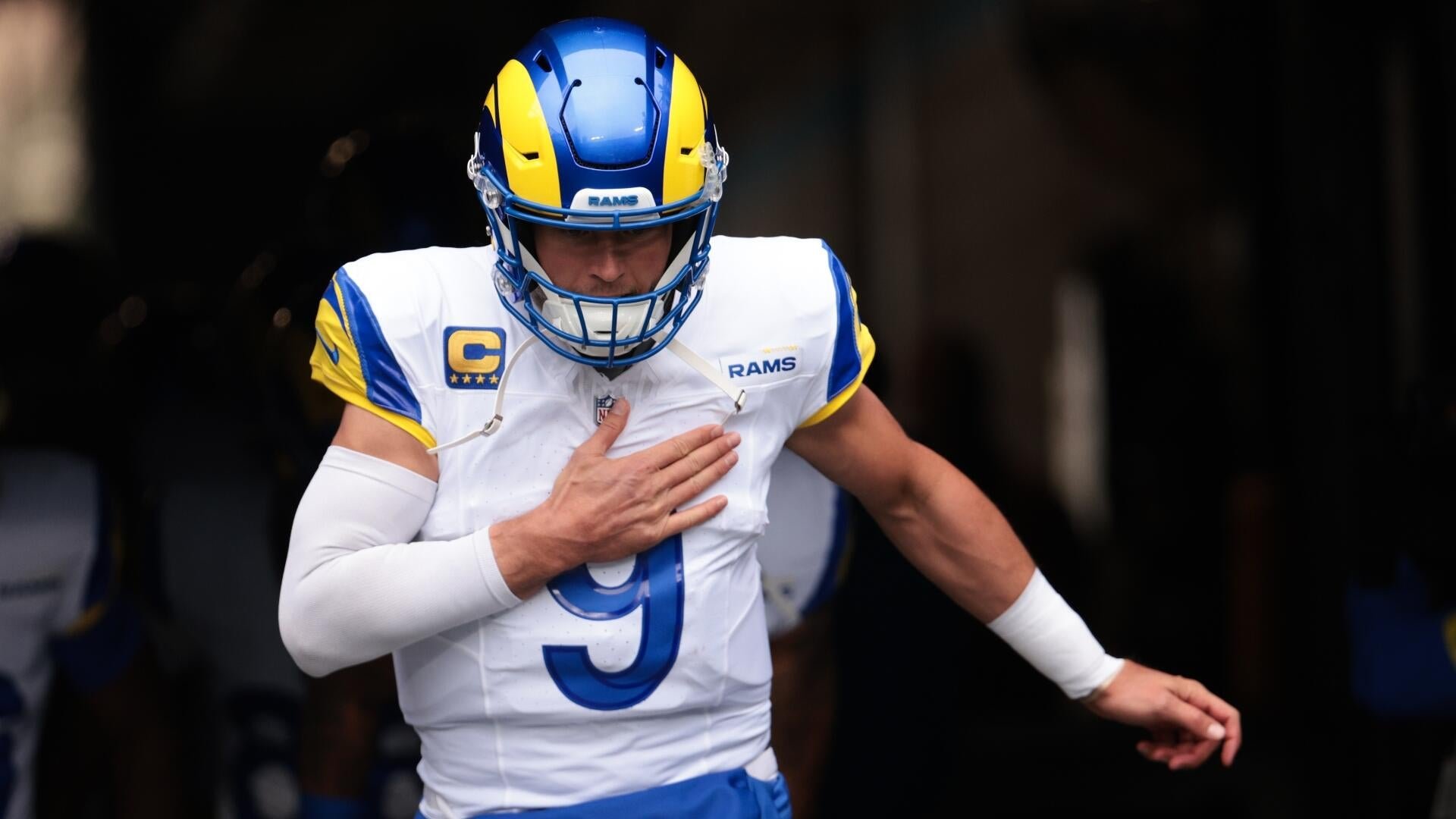 A Los Angeles Rams football player wearing a white jersey with the number 9 and a captain's "C" patch runs forward with his hand over his chest.