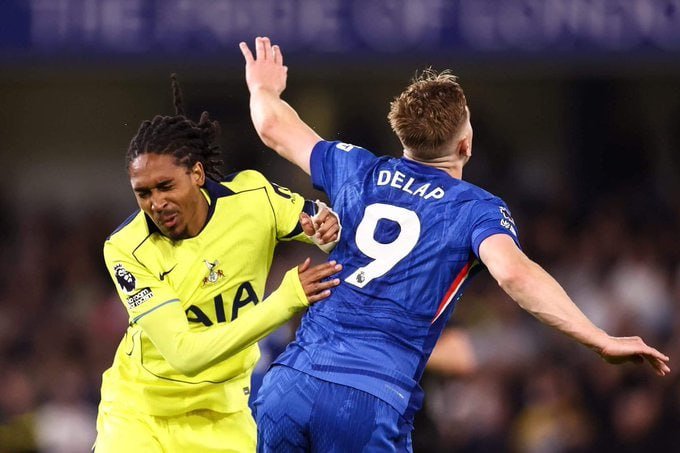 Two soccer players, one in a yellow Tottenham jersey and another in a blue jersey reading "DELAP 9," collide during a match.
