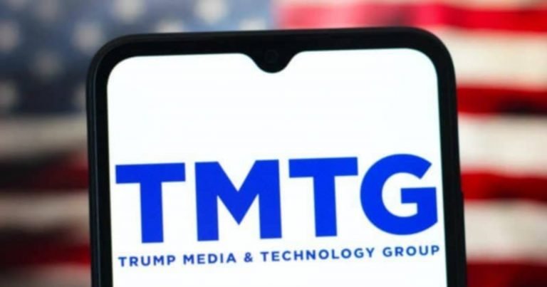 A smartphone displays the blue "TMTG - Trump Media & Technology Group" logo against a blurred American flag background.