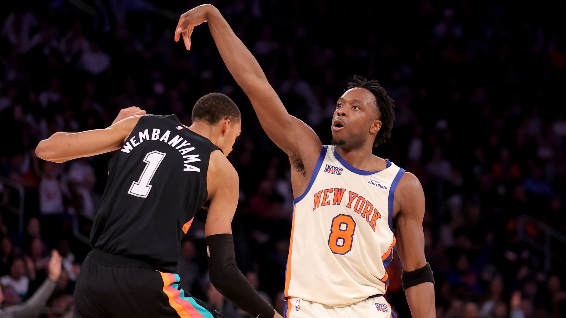 Knicks player #8 raises his arm defensively while a Spurs player wearing jersey #1 labeled "WEMBANYAMA" faces him during a basketball game.