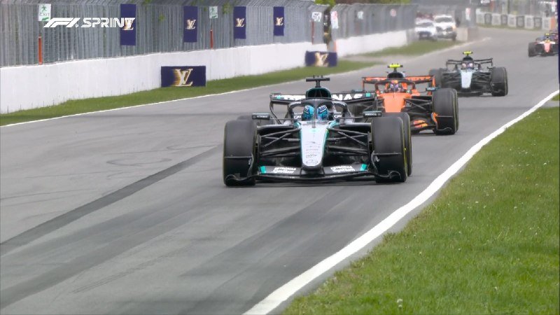 Formula 1 race cars line up on a track beside a barrier displaying Louis Vuitton banners, with the "F1 SPRINT" logo visible in the corner.