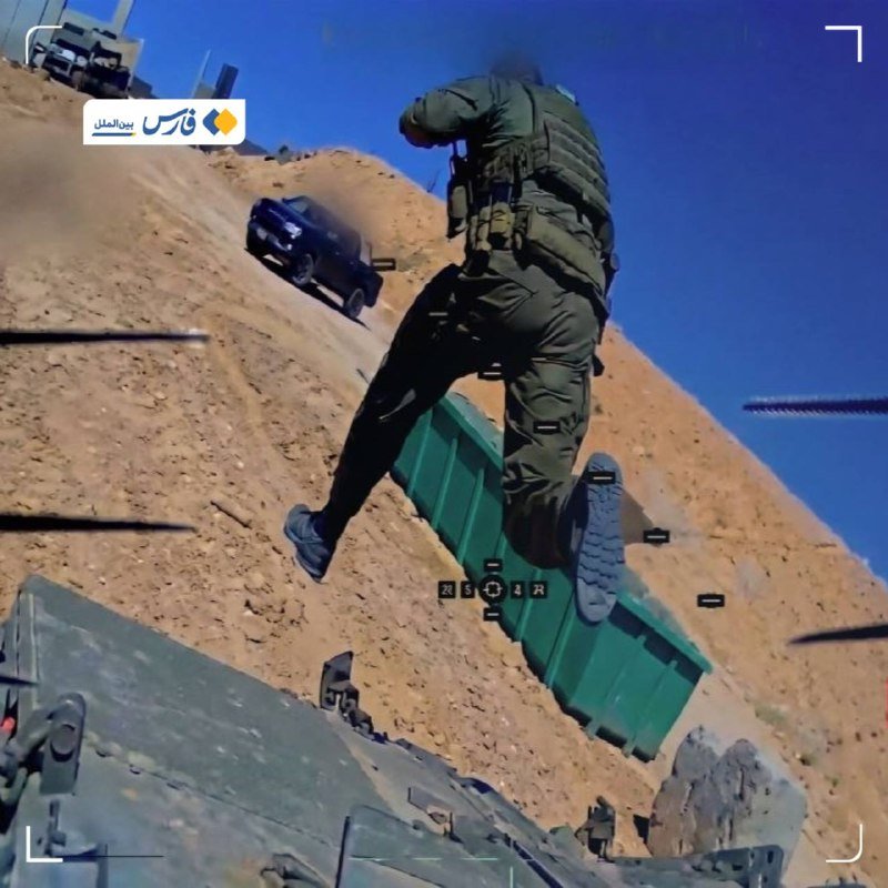 A soldier in tactical gear jumps off a green container in a sandy, desert-like environment with vehicles visible in the background.