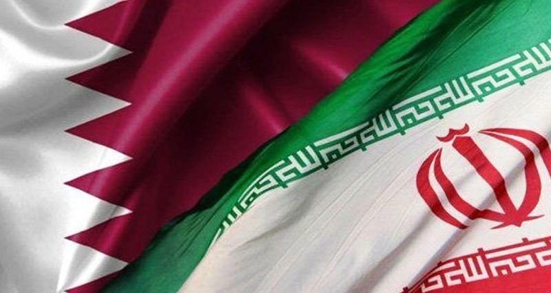 The flags of Qatar and Iran are shown side by side, their fabric rippling.
