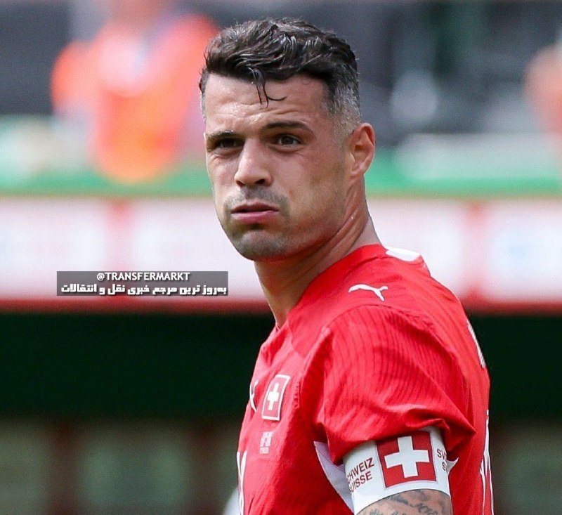 A man wearing a red Swiss national football jersey with a Puma logo stands on a pitch during a match.