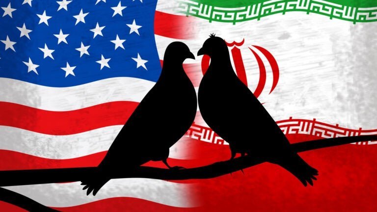 Two black bird silhouettes face each other on a branch, set against a split background showing the U.S. flag on the left and the Iranian flag on the right.