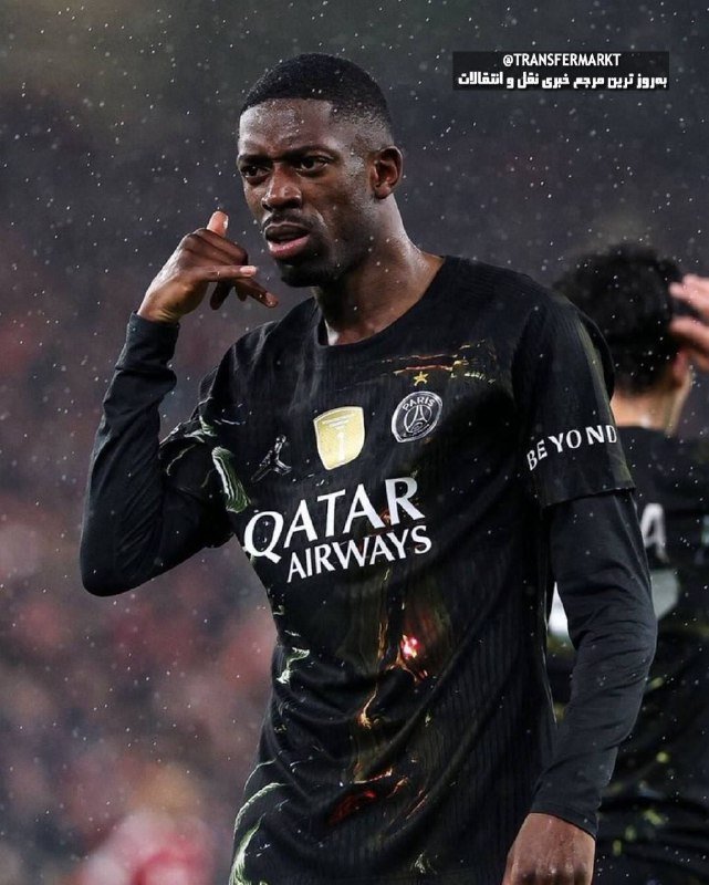A footballer in a black Paris Saint-Germain jersey with "QATAR AIRWAYS" branding points forward with one hand during a rainy match.