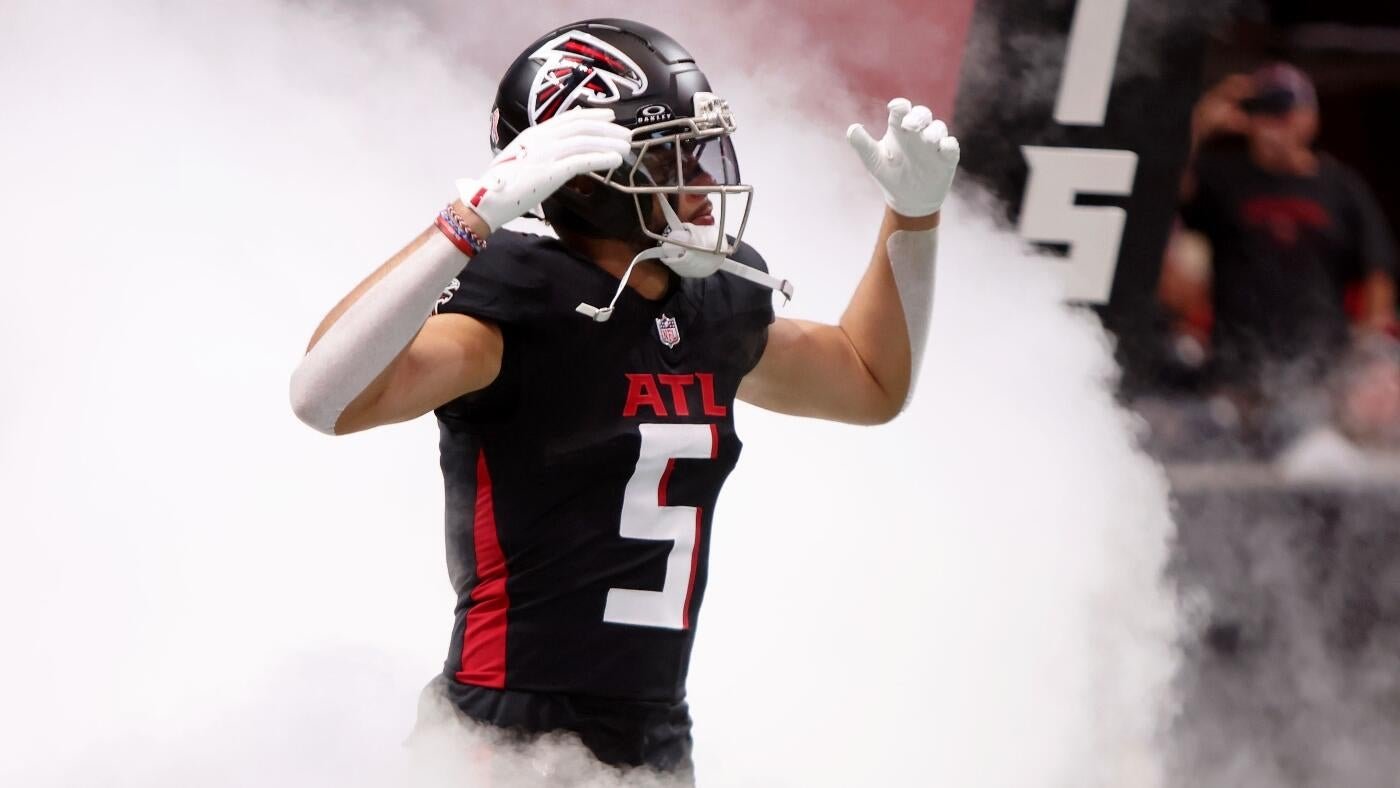 An Atlanta Falcons football player wearing a black jersey with the number 5 stands amid white smoke with both arms raised.
