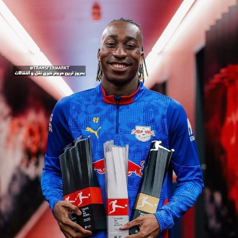 A smiling man in a blue RB Leipzig Puma training top holds three Bundesliga "Rookie of the Month" trophies.