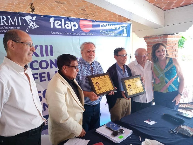 Six people stand at a table holding two framed certificates in front of a banner reading "FELAP" and "CONALPE."