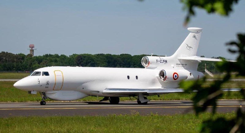 A white tri-jet aircraft with registration "F-ZJPM" and a French roundel sits on a runway, with trees and a radar tower visible in the background.