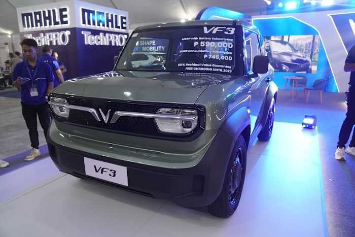 A green VF3 SUV is displayed at an indoor auto show, featuring pricing details on its windshield and positioned near a MAHLE TechPRO booth.