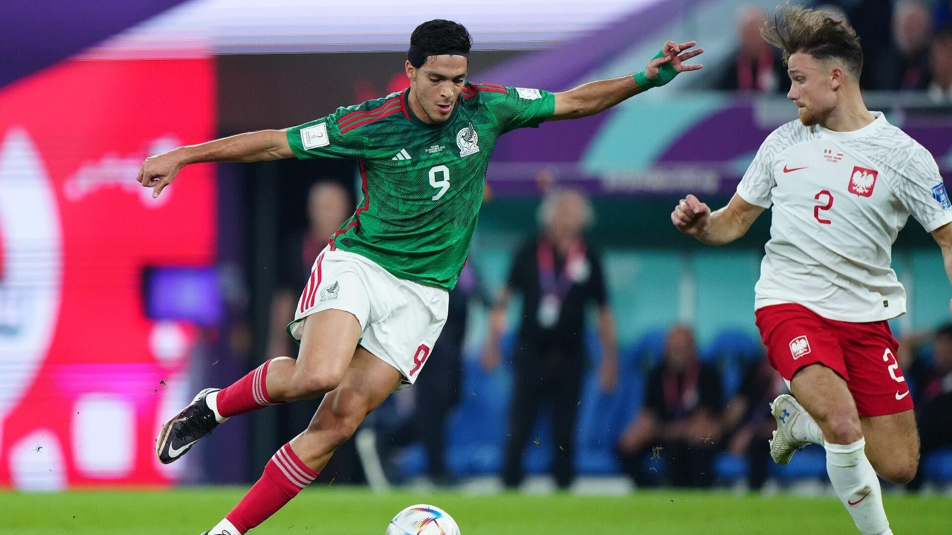 A soccer player in a green Mexico jersey (#9) dribbles the ball past a defender in a white Poland jersey (#2) during a match.