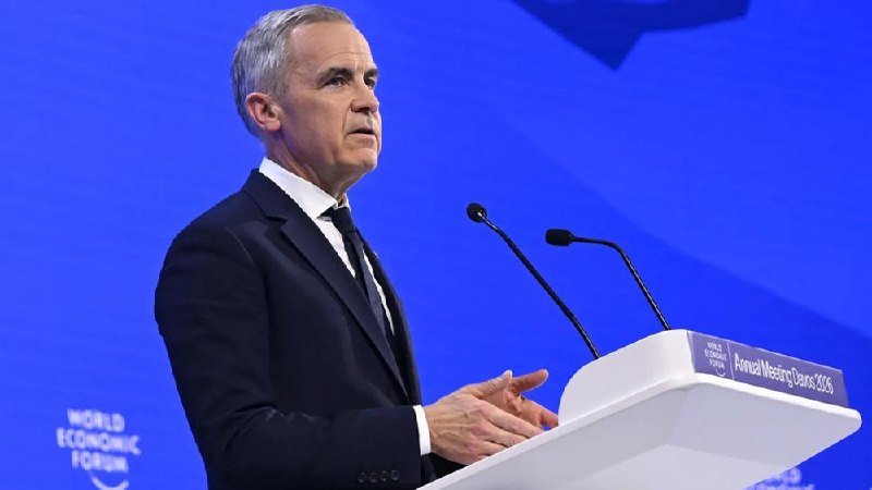 A gray-haired man in a dark suit speaks at a podium labeled "Annual Meeting Davos 2026" against a blue "World Economic Forum" backdrop.