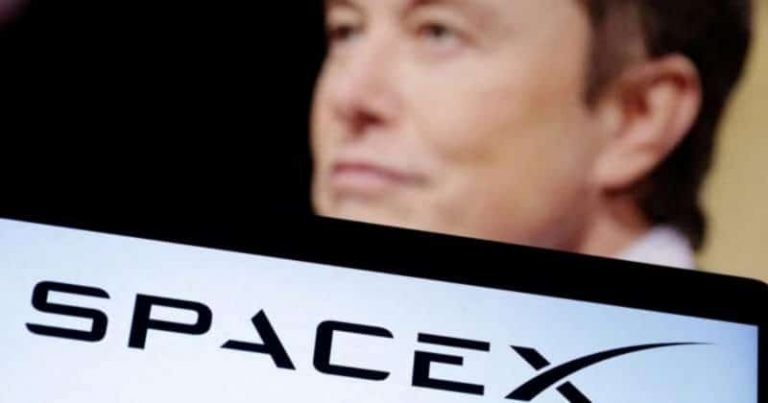 A man's face appears blurred in the background behind a screen displaying the SpaceX logo.