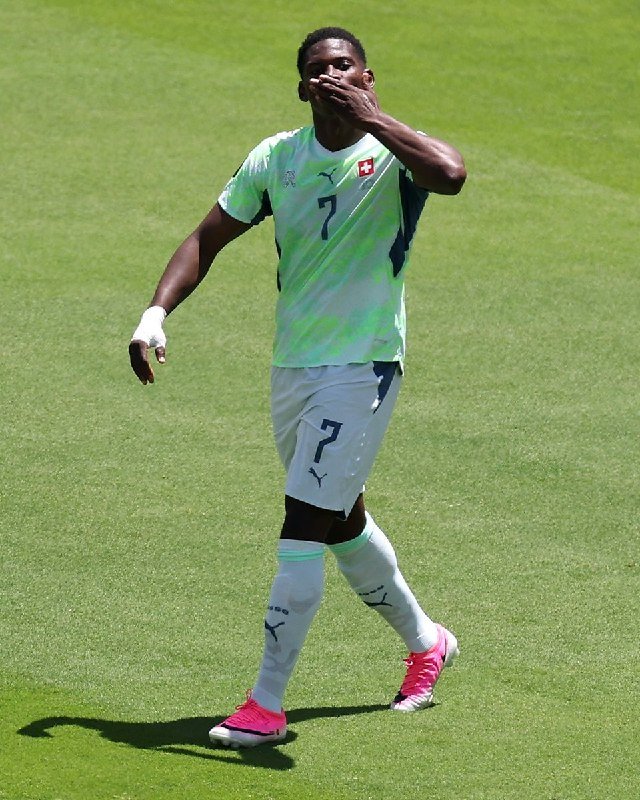 A soccer player wearing the number 10 Argentina jersey celebrates with arms outstretched on a green pitch.