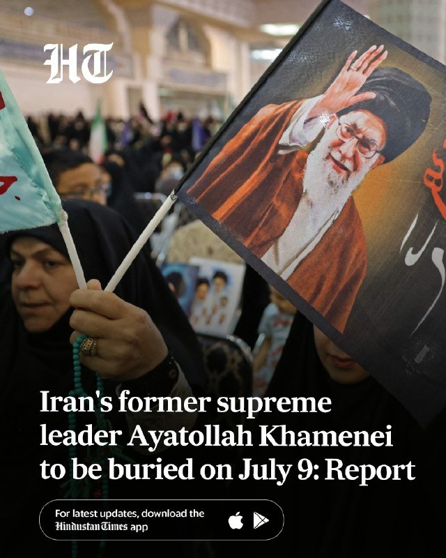 A person waves a large Iranian flag at night while others around them raise their hands in celebration, with a streetlight illuminating the scene.