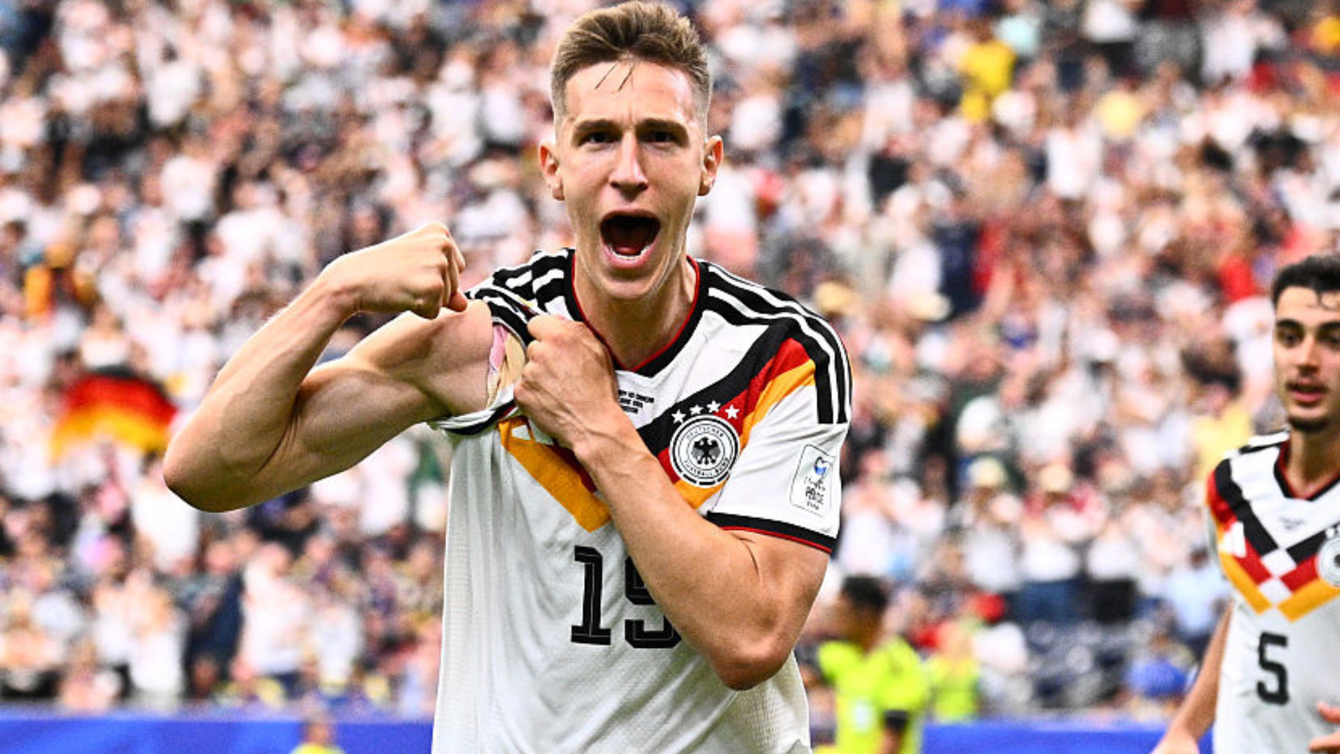 Graphic illustration showing a soccer player in a yellow jersey celebrating, with a scoreboard reading Ecuador 2, Germany 1, and "FIFA World Cup 2026" text visible.