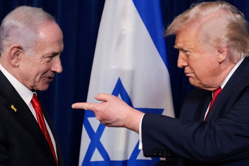 Two men in suits face each other in front of an Israeli flag; the man on the right points toward the man on the left.