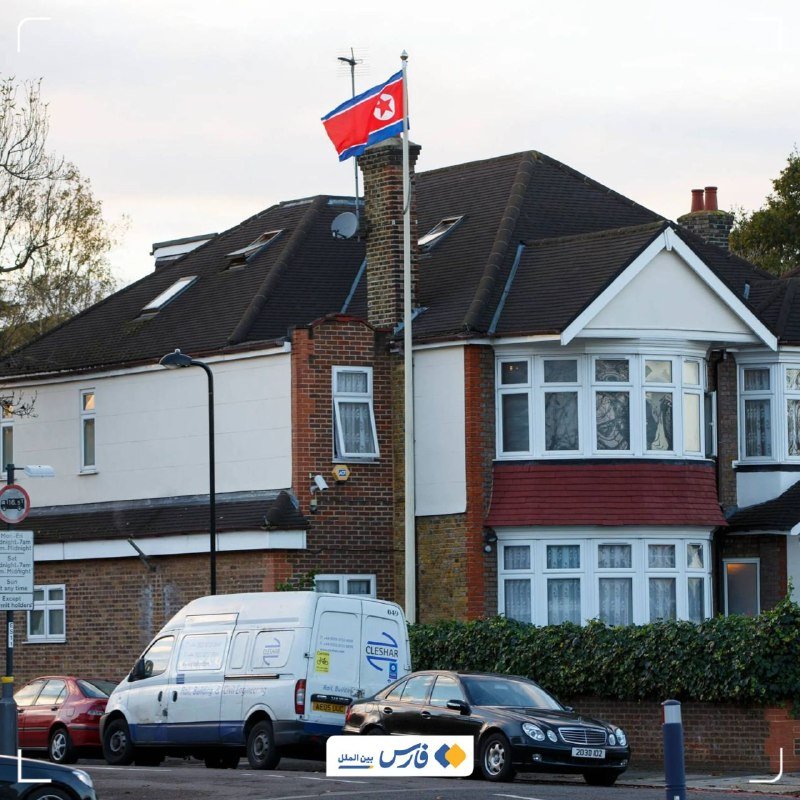 The North Korean flag flies from a pole mounted on the roof of a residential building.