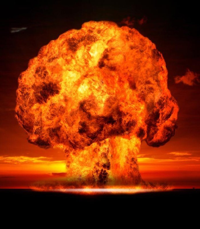 A large orange and yellow mushroom-shaped fireball rises from a dark horizon against a reddish sky.