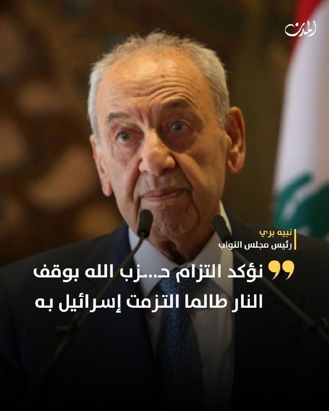 An older man in a dark suit and tie speaks at two microphones with Arabic text overlaid.