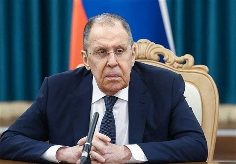 A man in a dark suit and blue tie speaks at a podium with Russian and NATO flags displayed, captioned "Lavrov Warns of Risk of NATO-Russia Nuclear Exchange" via The Epoch Times.