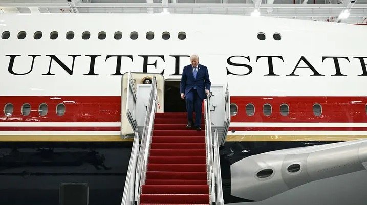 A blonde woman in a beige blazer sits on an ornate gold chair against a red backdrop, with an inset photo of a gray-haired man and the caption "Italy Cancels US Visit Over Trump's Reported Comments on Meloni."