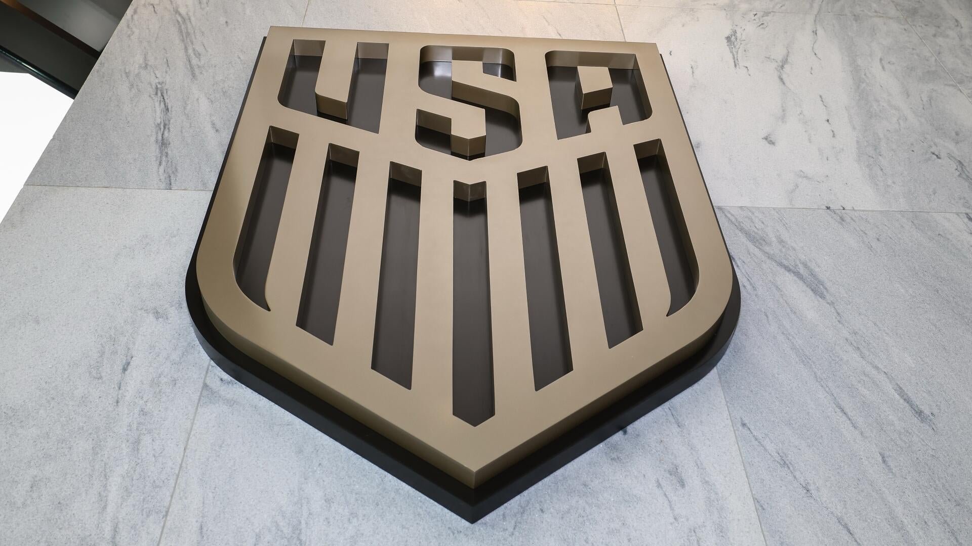 A large shield-shaped metallic USF logo rests on a light gray marble-tiled floor.