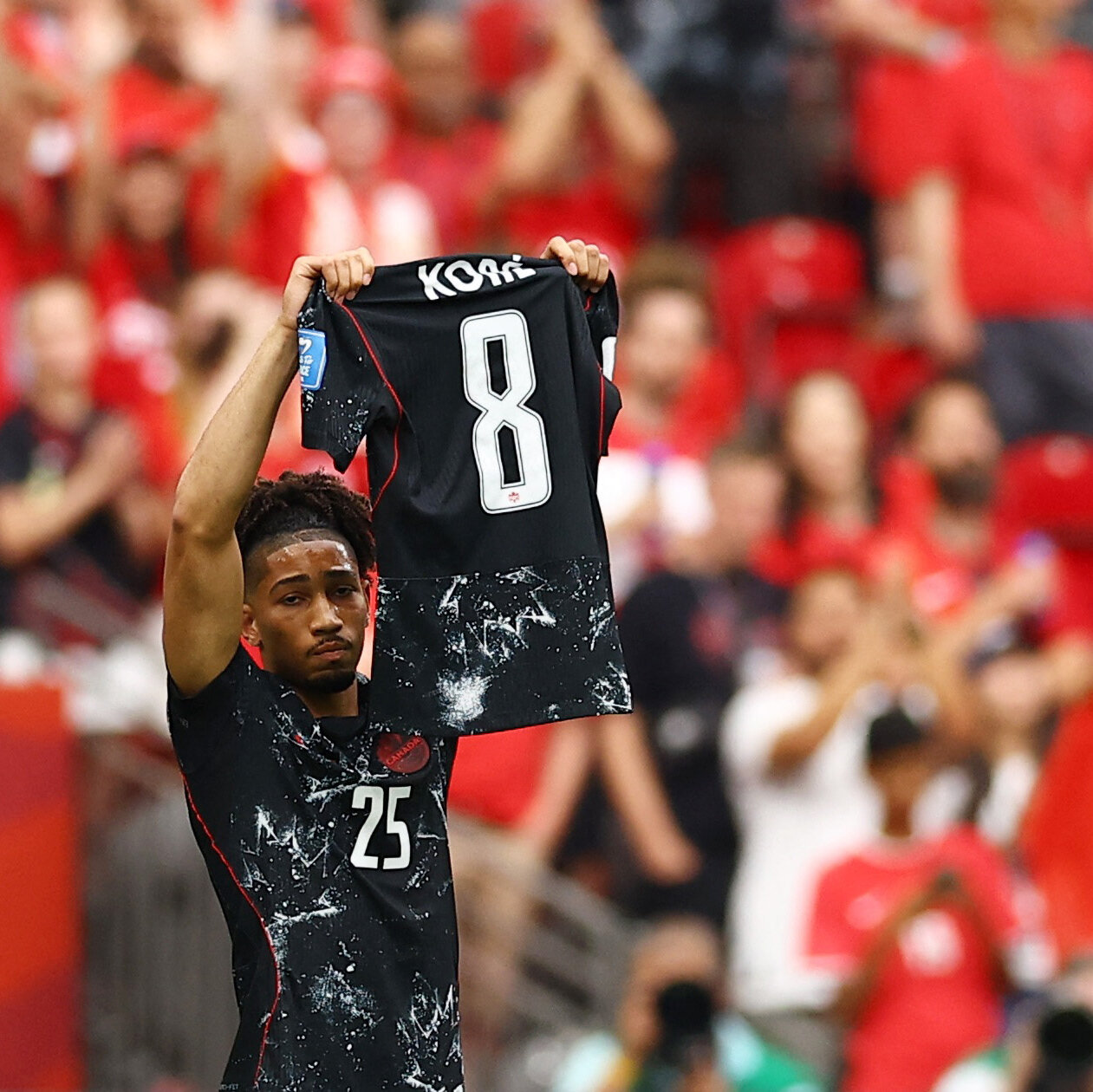 A blonde soccer player in a black jersey with the number 9 stands with hands on hips in a stadium.