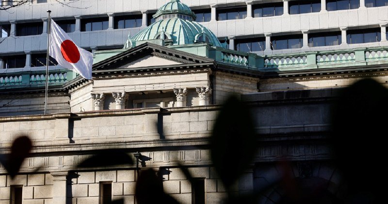 A Japanese flag flies at half-mast on a classical stone building with a green copper dome, while silhouetted figures stand in the foreground.