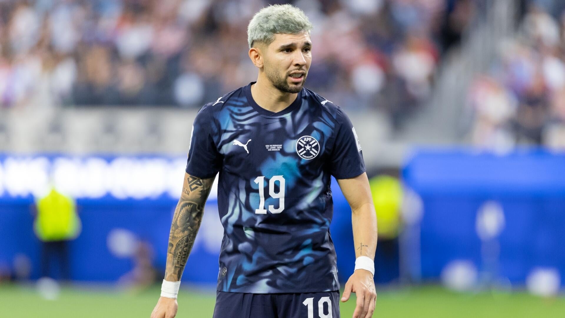 Promotional FIFA World Cup 2026 graphic showing two players facing each other in profile, with stats reading "MESSI 18 GOALS" and "MBAPPÉ 16 GOALS" beneath the question "WHO COMES OUT ON TOP?"