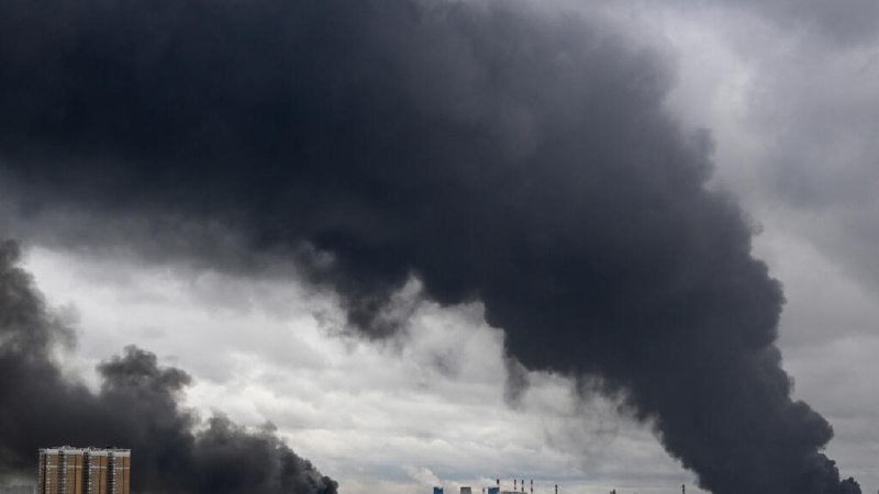 A bespectacled man in a dark suit and tie wearing an earpiece sits before a backdrop displaying Cyrillic text, with the headline "Russia bans diesel exports after Ukraine's refinery attacks" below.