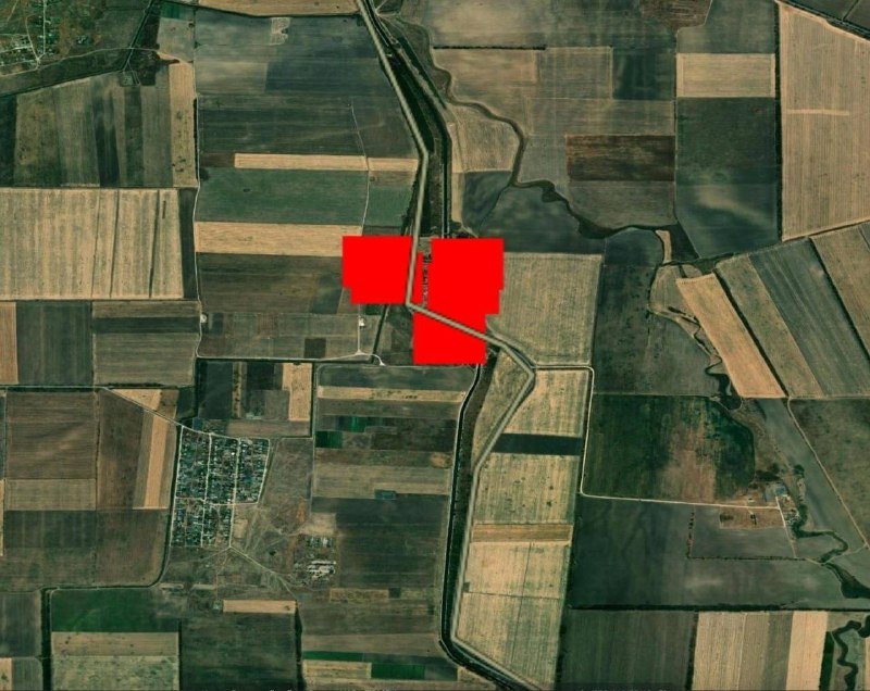 An aerial satellite image shows a patchwork of agricultural fields with three red rectangular graphics overlaid near the center, alongside a small residential area in the lower left.