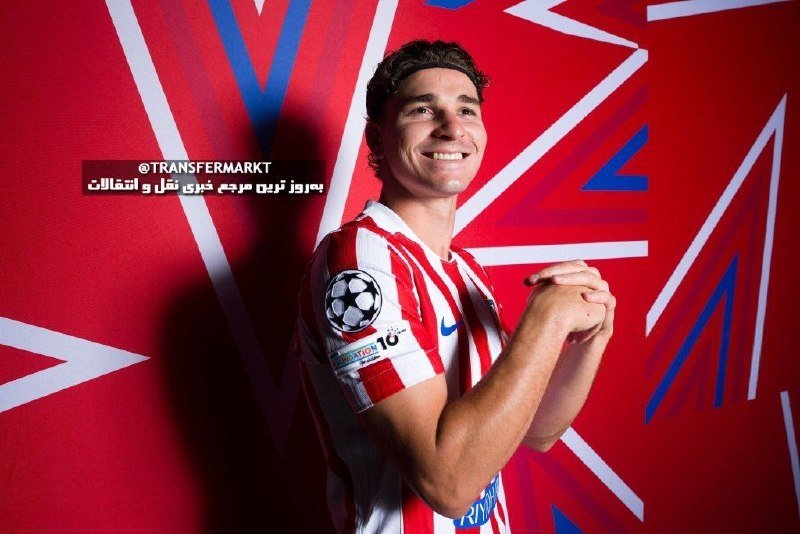 A smiling soccer player in a red and white striped jersey poses against a red star-patterned backdrop, with "Transfermarkt" and Arabic text visible.