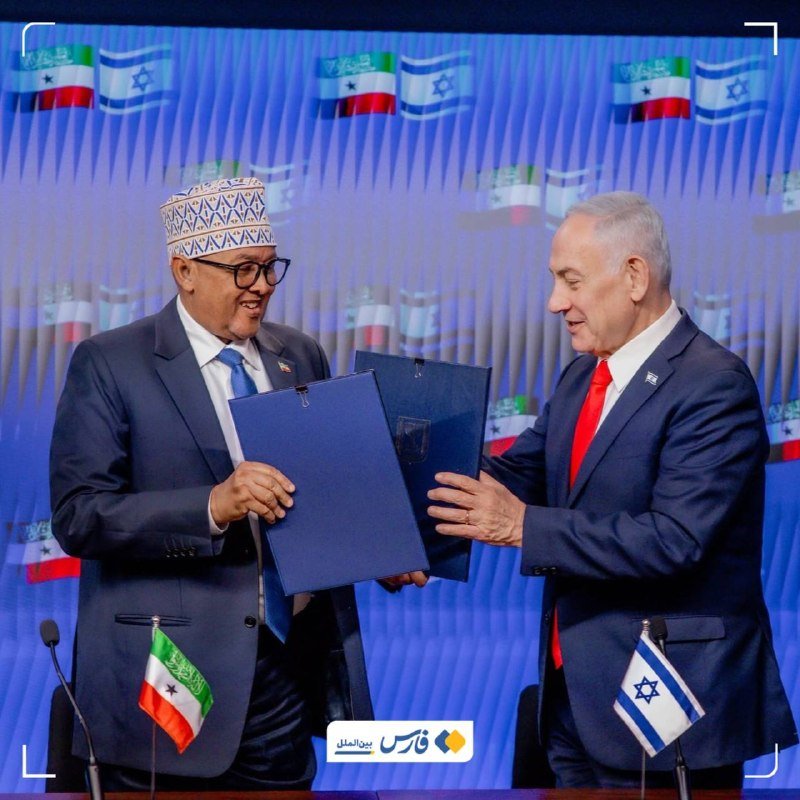 A gray-haired man in glasses and a dark suit stands at a microphone, with the Iranian flag and a "Ministry of Foreign" backdrop behind him.