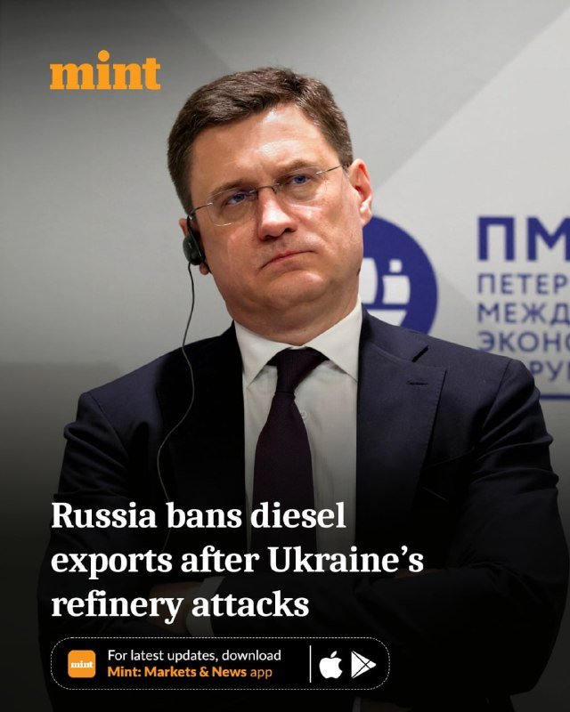 A bespectacled man in a dark suit wears an earpiece at a St. Petersburg International Economic Forum panel.