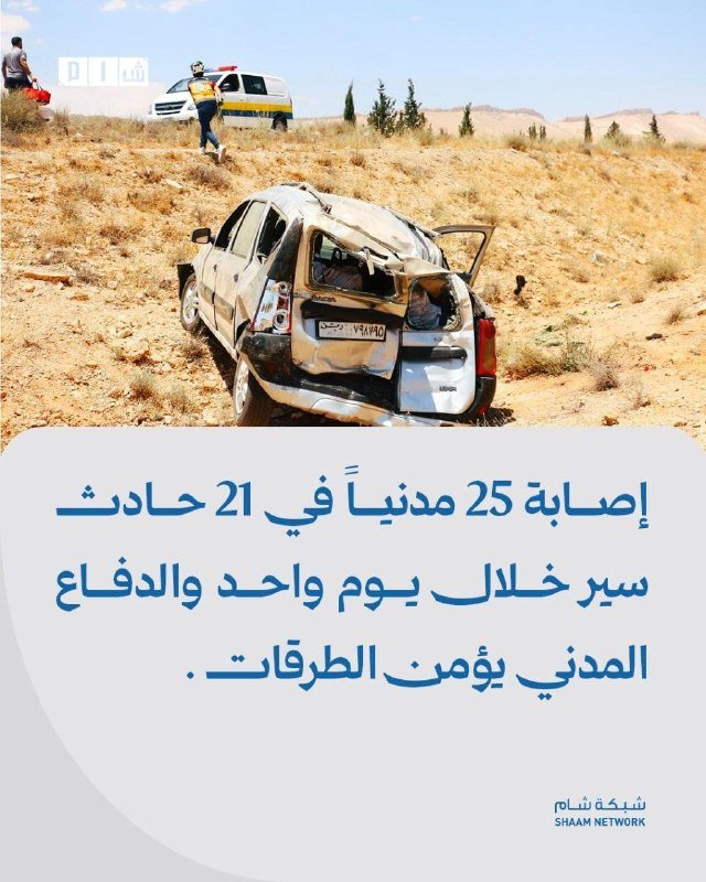 A burned, damaged SUV sits in a barren desert landscape while an emergency responder walks toward a nearby ambulance, below Arabic text reporting a traffic accident.