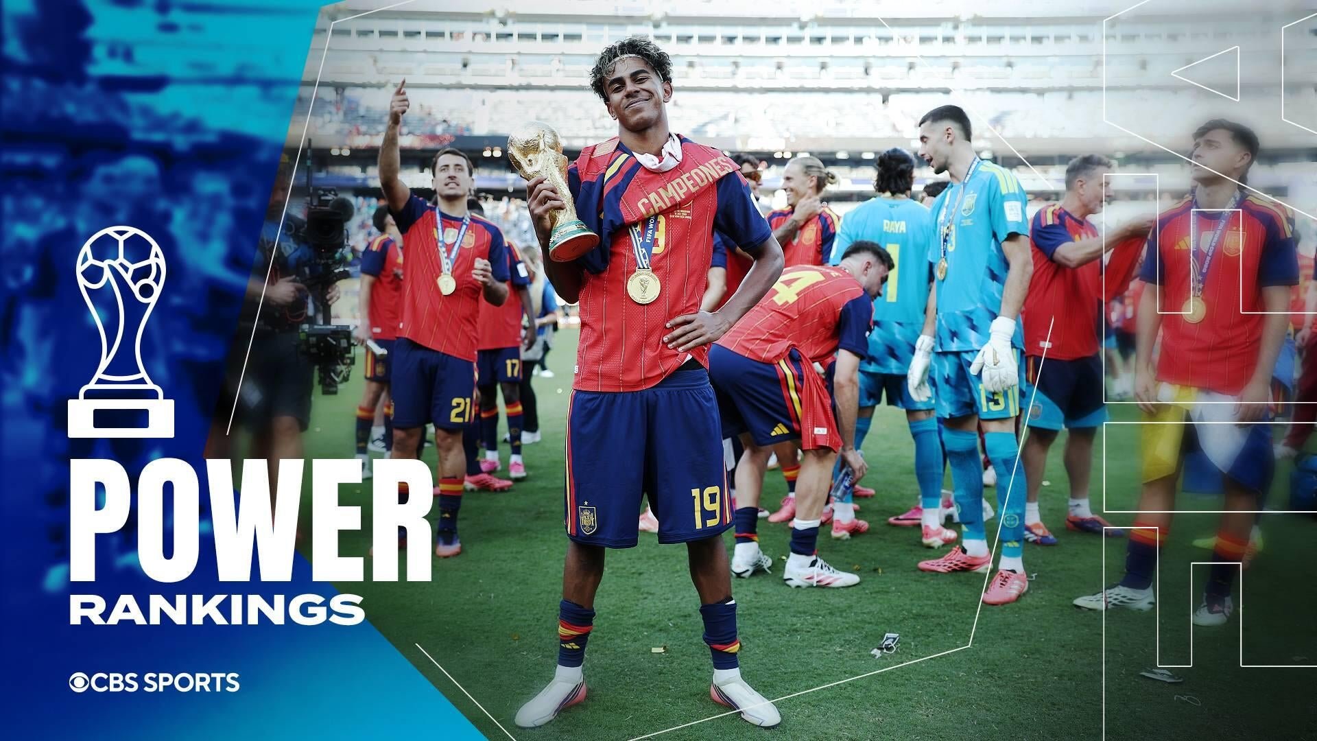 Soccer players in red jerseys celebrate on a stadium field, with one holding a golden World Cup trophy and wearing medals.