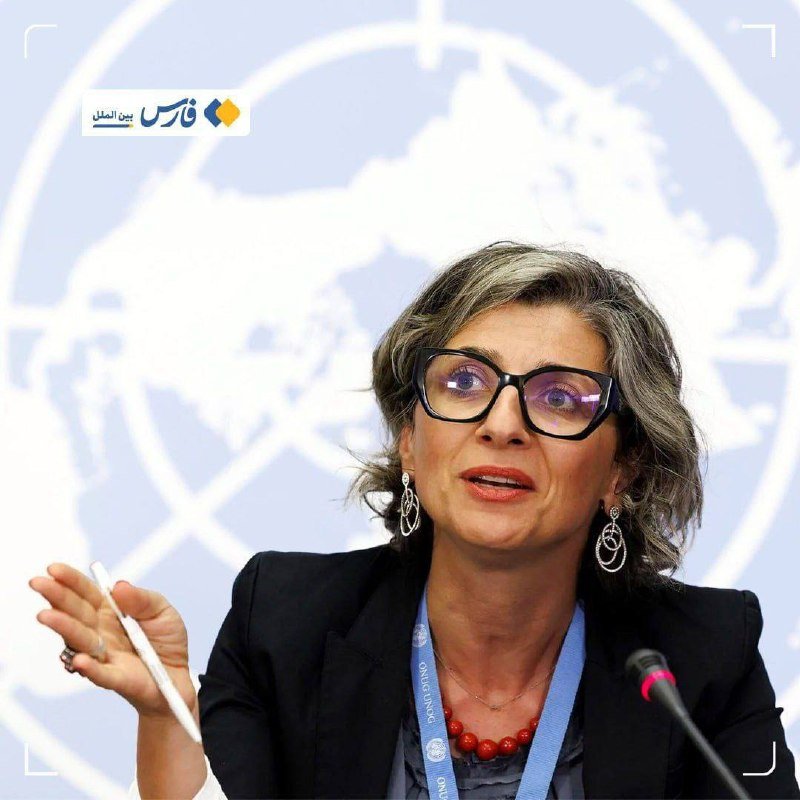 A woman with glasses and a red necklace gestures while speaking at a podium microphone, with a United Nations logo backdrop and a bank logo visible.